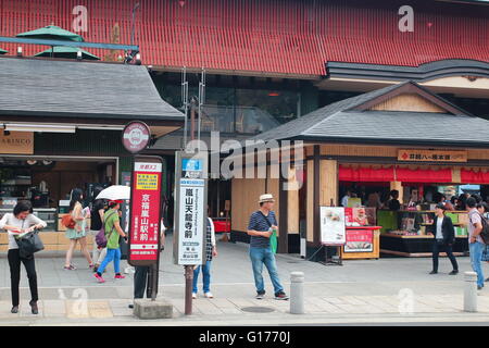 I viaggiatori in attesa nella parte anteriore della fermata del bus a città Arashiyama, Kyoto Foto Stock
