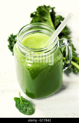 Un sano frullato verde con paglia in una giara mug su sfondo bianco Foto Stock