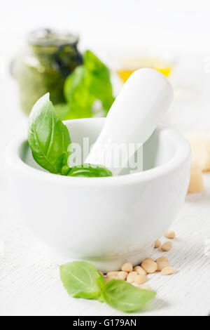 Ceramica mortaio con pestello e Pesto ingredienti su bianco Foto Stock