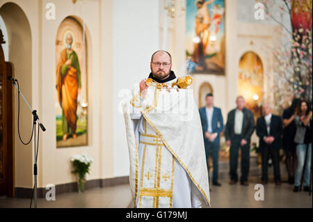 LVIV, Ucraina - 8 Maggio 2016: il sacerdote con un turibolo con la cerimonia della prima Comunione nella Chiesa di San Pietro il Grande di Ukrai Foto Stock