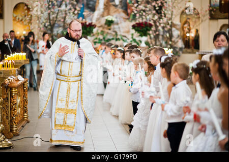 LVIV, Ucraina - 8 Maggio 2016: il sacerdote con la cerimonia della prima Comunione nella Chiesa di San Pietro il Grande di Greco ucraino Cat Foto Stock