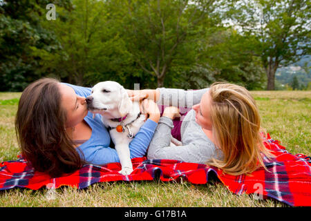 Due giovani donne con cane da compagnia, giacente su una coperta in posizione di parcheggio Foto Stock