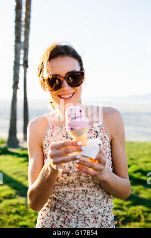 Ritratto di giovane donna a mangiare il gelato in cono costa, Venice Beach, California, Stati Uniti d'America Foto Stock