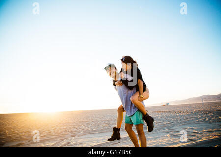 Giovane ragazza dando una piggy back a beach, la Spiaggia di Venice, California, Stati Uniti d'America Foto Stock