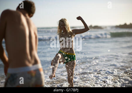 Coppia sulla spiaggia spruzzi in ocean Foto Stock