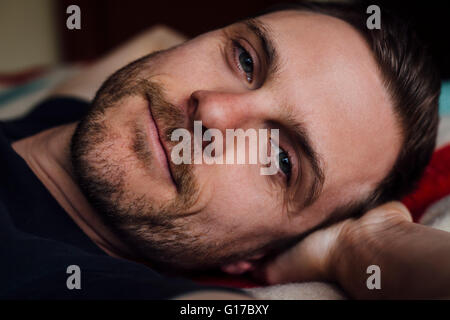 Close up ritratto di bello fiducioso uomo sul letto con le mani dietro la testa Foto Stock