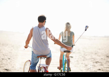 Vista posteriore della bicicletta uomo prendendo un selfie presso la spiaggia di Venezia, Los Angeles, California, Stati Uniti d'America Foto Stock