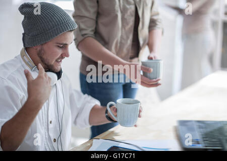 Collega distribuendo del caffè in ufficio loft Foto Stock