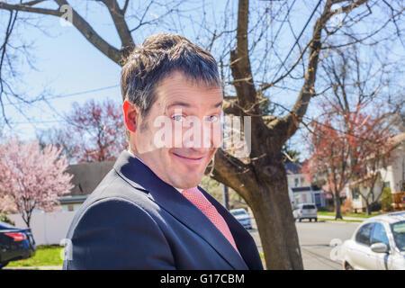 Ritratto di business man in zona residenziale tirando il viso a fotocamera a sorridere Foto Stock