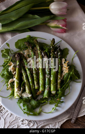 Asparagi arrosto con formaggio parmigiano su un letto di rucola Foto Stock