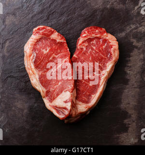 Forma di cuore crudo fresco bistecca di carne controfiletto su pietra ardesia sfondo Foto Stock