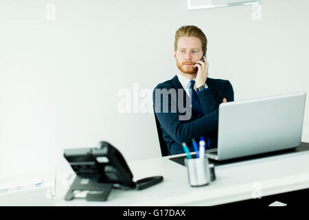 Oung redhair uomo che parla al telefono cellulare in ufficio Foto Stock