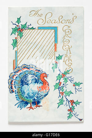Natale carta stampata con un disegno di una Turchia e spruzzi di holly e goffrato 'i saluti della stagione' in oro su un pallido blu Foto Stock
