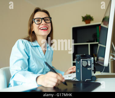 Giovane donna artista disegno qualcosa sulla tavoletta grafica presso l'ufficio a casa Foto Stock