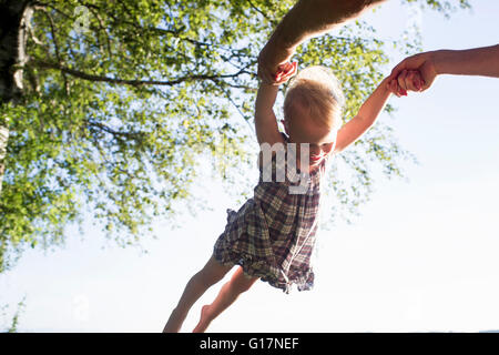 Padre swinging Baby girl in aria, esterni a basso angolo di visione Foto Stock