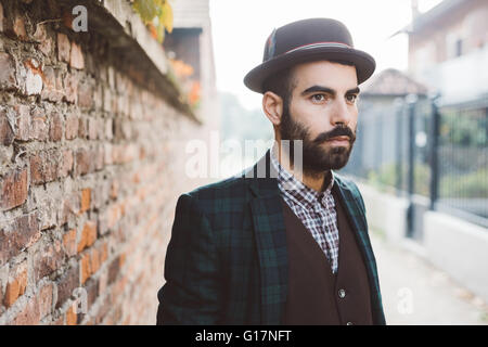 Giovane uomo in attesa accanto a un muro di mattoni Foto Stock