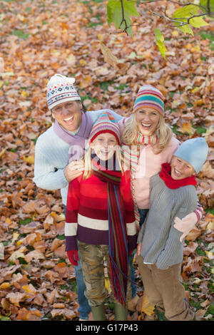 Ritratto di famiglia nel parco, circondato da foglie di autunno, sorridente, vista in elevazione Foto Stock