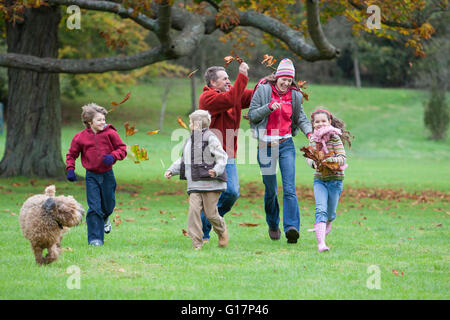Famiglia ingannare intorno nel parco, gettando le foglie di autunno Foto Stock