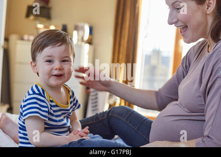 Vista laterale della gravidanza la madre e il bambino guardando sorridente della fotocamera Foto Stock