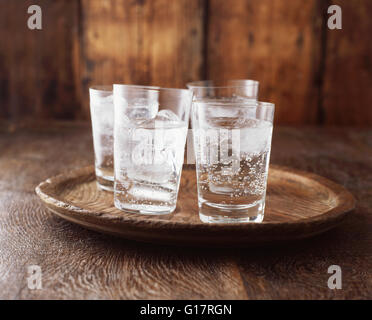 Acqua frizzante nel bicchiere con ghiaccio su vintage piatto in legno Foto Stock