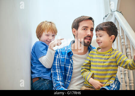 Padre e figli seduti sulla scalinata Foto Stock