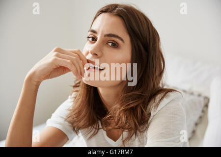 Ritratto di giovane e bella donna seduta sul letto Foto Stock