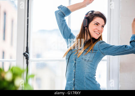 Giovane donna ballando nella parte anteriore del city apartment finestra Foto Stock