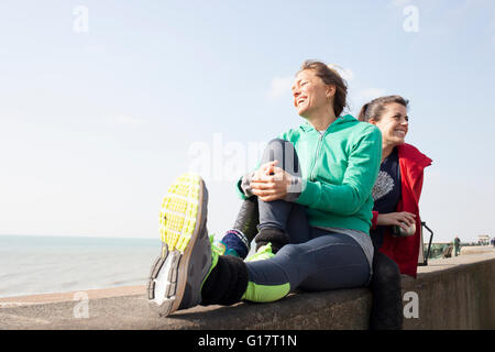 Due femminile prendendo una pausa caffè sulla parete presso la spiaggia di Brighton Foto Stock