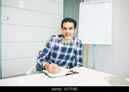 Ritratto di giovane maschio designer che lavorano su notebook in ufficio Foto Stock