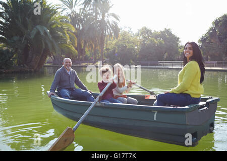 Famiglia in barca a remi sul lago di guardare fotocamera a sorridere Foto Stock