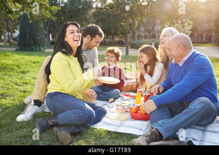 Multi generazione famiglia seduto sull'erba con picnic Foto Stock