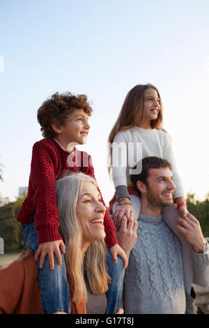 Ragazzo e una ragazza seduta sulla nonna e padri di spalle, guardando lontano sorridente Foto Stock