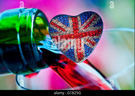 In inglese il concetto di vino con amore a forma di cuore frizzante riflettente Union Jack Flag motif e colorata di bottiglie di vino dietro versamento Foto Stock
