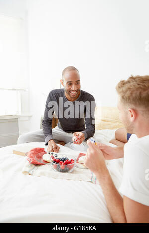 Coppia omosessuale sul letto avente la prima colazione Foto Stock