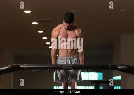 Giovani Bodybuilder facendo Dips sulla barra esercizio tricipiti sulla macchina in palestra Foto Stock