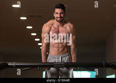 Giovani Bodybuilder facendo Dips sulla barra esercizio tricipiti sulla macchina in palestra Foto Stock