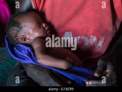 Toposa madre con il suo neonato nel suo rifugio, valle dell'Omo, Kangate, Etiopia Foto Stock