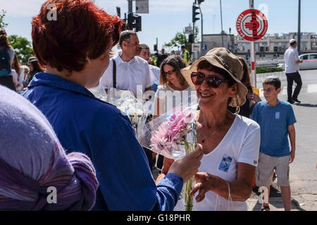 Gerusalemme, Israele. 11 Maggio, 2016. Membri di movimenti giovanili distribuire i fiori per le decine di migliaia di persone che arrivano a monte Herzl Cimitero Militare durante Yom Hazikaron Memorial Day. Questo giorno memoriale commemora 23,477 soldati caduti e le donne e 2,576 vittime del terrore. Credito: Nir Alon/Alamy Live News Foto Stock