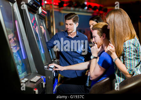 Giovane gruppo di persone il gioco d'azzardo in un casinò giocare slot e macchine varie Foto Stock