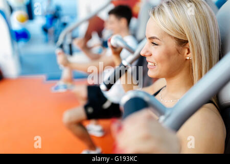 Persone che esercitano in palestra su varie macchine Foto Stock