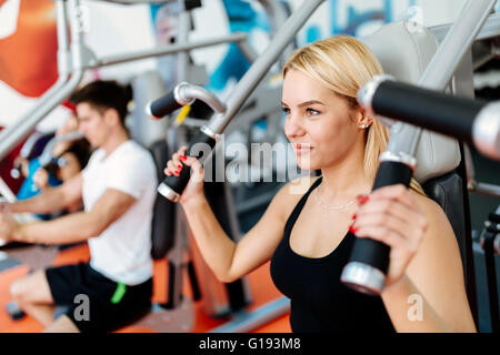 Persone che esercitano in palestra su varie macchine Foto Stock