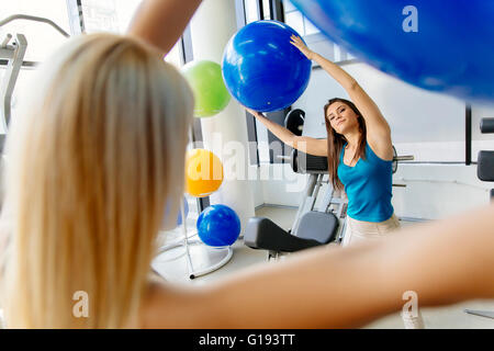 Le donne, amici della formazione in palestra e stretching i muscoli con palla medica Foto Stock