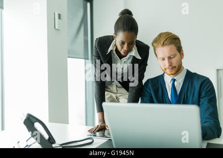 La gente di affari di parlare e di analizzare in un ufficio escursioni nella parte anteriore di un notebook Foto Stock