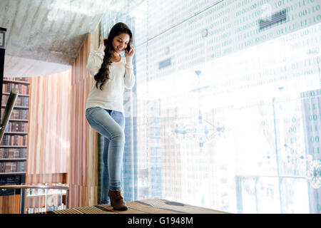 Imprenditrice usando il telefono in ambienti chiusi e sorridente Foto Stock