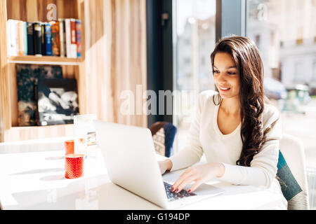 Bella bruna utilizzando notebook in cafe Foto Stock