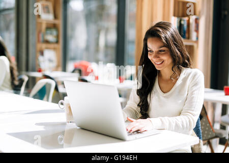 Bruna lo studio sul laptop e godendo di caffè Foto Stock