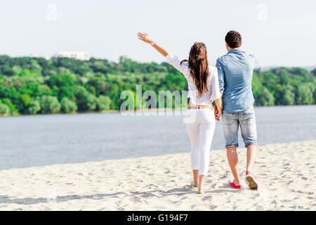 Giovane tenendo le mani e piedi su di una spiaggia di sabbia Foto Stock