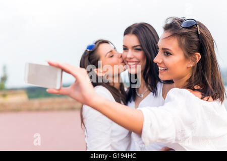 Tre felici donne prendendo un selfie di se stessi e giocare intorno Foto Stock