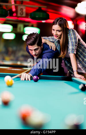 Giovane uomo bello e donna flirtare mentre giocando a biliardo Foto Stock