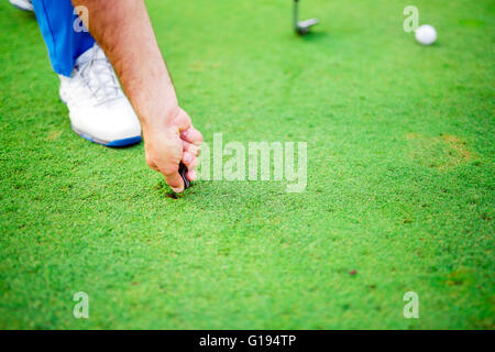 Giocatore di Golf riparazione foro su un verde erba superficie Foto Stock